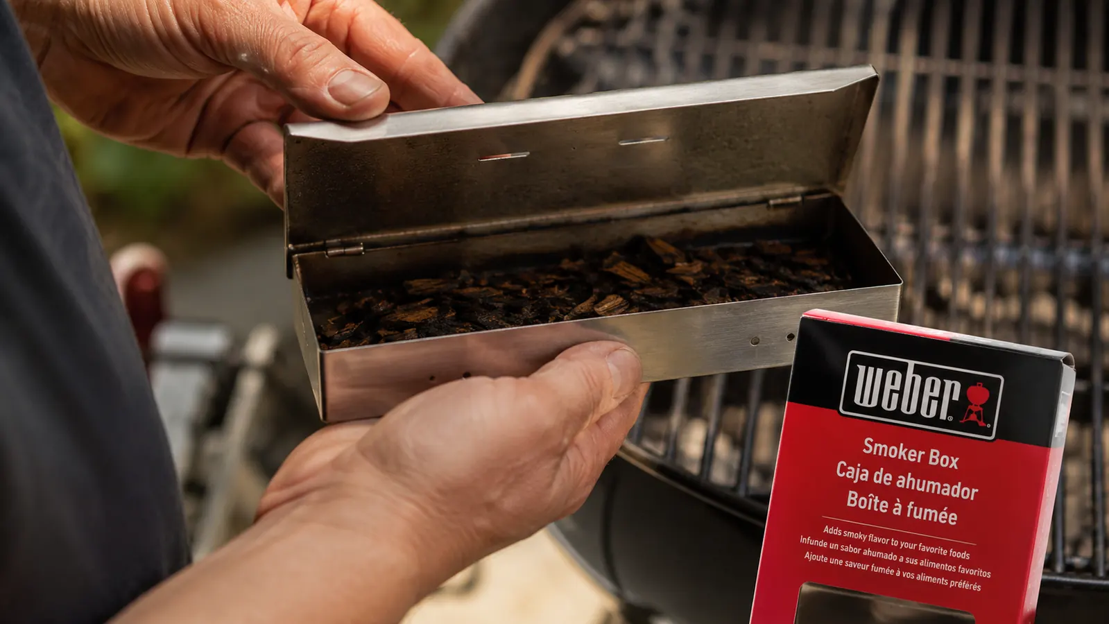 Close-up of Weber smoker box lid with ventilation slots after a long cook, showing darkened stainless interior